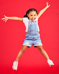 Image showing Excited, playful and portrait of a girl jumping while isolated on a red background in a studio. Youth, smile and child with freedom, energy and happiness while playing with a jump on a backdrop