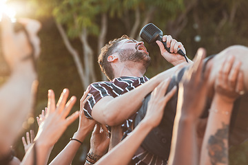 Image showing Crowd, surfing and man singing at party, outdoor music festival or social gathering. Microphone, energy and male singer diving in audience group at performance event, celebration or crazy fun weekend