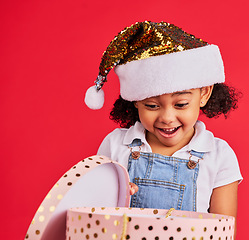 Image showing Wow, christmas and gift with a black girl on a red background in studio for festive celebration or surprise. Box, present or kids with a happy female child celebrating a holiday tradition in december