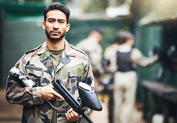 Image showing Portrait, paintball and camouflage with a sports man holding a gun for a game or competition. Fitness, exercise and serious with a male athlete carrying a weapon or marker for military training