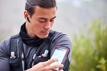 Image showing Fitness, phone and man hiking outdoor, trekking in nature with earpods, music and workout with exercise app. Health, wellness and body training with mockup, athlete listen to podcast with 5g on hike