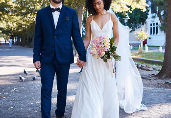 Image showing Love, wedding and couple with flowers holding hands outdoors at park together. Marriage, diversity or affection, care or romance of man, woman or bride and groom walking with bouquet of roses.