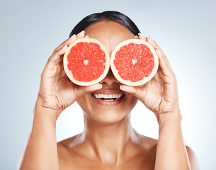 Image showing Funny, fruit and woman use grapefruit for a joke covering her eyes isolated against a studio blue background. Health, beauty and skincare model smiling due to vitamin c from juicy citrus