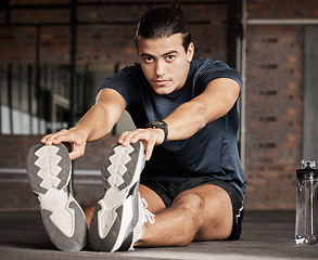 Image showing Portrait, fitness and stretching with a man athlete in gym getting ready for his workout routine. Exercise, health and warm up with a handsome young male training in a performance center for wellness