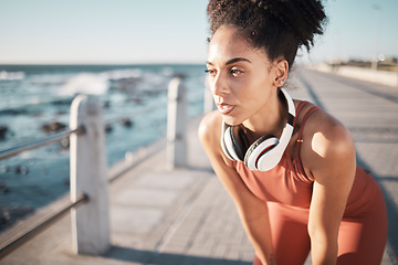 Image showing Thinking, fitness and breathing with a black woman runner on the promenade for cardio or endurance exercise. Running, workout or health with a young female athlete training outdoor by the sea