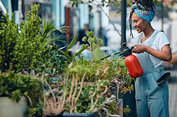 Image showing Water, flowers or black woman gardening in small business shop for healthy leaf or organic plants growth. Irrigation, store manager or girl entrepreneur watering floral agriculture with a happy smile