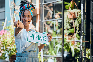 Image showing Small business, manager or black woman with a hiring sign at door entrance in floral retail store. Advertising, marketing and happy entrepreneur smiles pointing with job offer message at flower shop