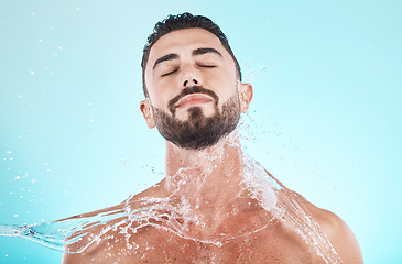 Image showing Water, splash and skincare with face of man for shower, self care and natural cosmetics. Luxury, hydration and refreshing with model for dermatology, wellness and cleaning in blue background studio