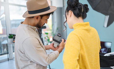 Image showing Photography, camera and photographer talking to a model while looking at pictures from a photoshoot. Discussion, studio and young cameraman choosing a image with a woman in a creative artistic studio