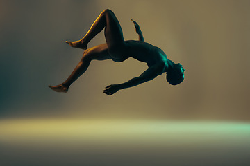 Image showing Shadow, black man and nude model in a studio background for creative art with lights. Isolated, floating and young naked body of a african person in the air with light showing dark art deco glow