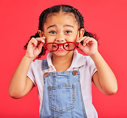 Image showing Eyes, glasses in hands and portrait of child with cute smile and isolated on red background. Vision, eyesight and happy playful expression, goofy little girl holding spectacles for eyesight in studio