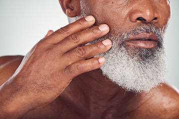 Image showing Hand, beard and face with a senior black man grooming in studio on a gray background for beauty or skincare. Skin, hygiene and cosmetics with a mature male indoor to promote facial hair maintenance