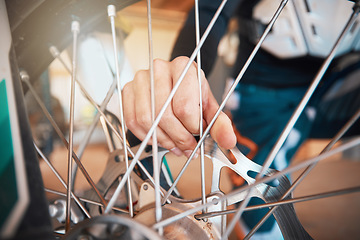 Image showing Motorcycle, wheel and hands on spokes with a man at work in a repair shop or maintenance garage. Bike, mechanic and service with a professional handyman working on a bicycle rim in a workshop