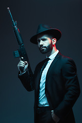 Image showing Man, suit or automatic rifle on dark studio background in secret spy, isolated mafia or crime lord security. Model, gangster or thinking hitman and gun in stylish, trendy or fashion clothes aesthetic