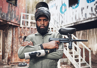 Image showing Arms crossed, portrait and black man with a paintball gun for fitness, training or a game. Exercise, focus and serious African player with a rifle for action, military work and outdoor competition