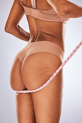 Image showing Woman, butt and measuring tape in studio for weight loss, diet and health progress on grey background. Body, size and girl model check, measure and slimming results while posing in underwear isolated