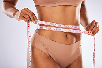 Image showing Measuring tape, stomach and woman in studio for wellness, weight loss and tummy tuck on grey background. Belly, measurement and girl model checking for progress, slimming and size after detox or diet