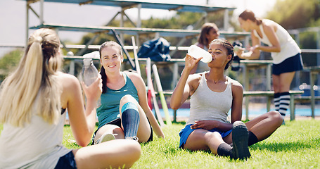 Image showing Sport, outdoor and women relax with water bottle, hydration and rest, field hockey athlete take training break. Health, wellness and fitness with sports team, collaboration and drink after workout