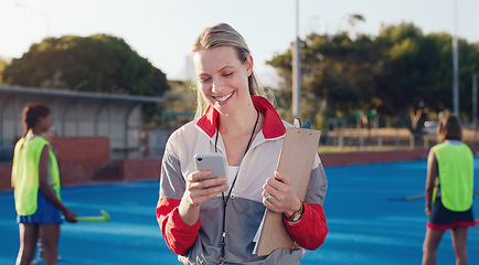 Image showing Hockey, coach and woman with phone at group training at a stadium for fitness, match and game. Sports, trainer and female laughing at meme, text or online message during morning cardio with players