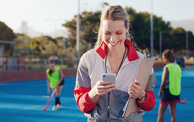 Image showing Hockey, trainer and phone of woman at a stadium for training, workout and fitness while browsing at match. Sports, coach and female happy, smile and excited for app, message and online text outside