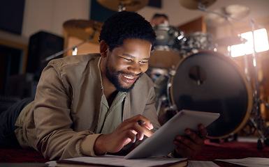 Image showing Black man musician, tablet and technology in music studio for social media, lyrics research or internet browsing. Tech, digital touchscreen and male artist web scrolling or editing audio at night.