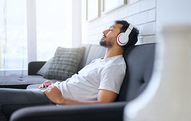 Image showing Music, relax and man with headphones on sofa in home living room streaming radio or podcast. Meditation, technology and male on couch in lounge listening to peaceful song, audio or album in house.