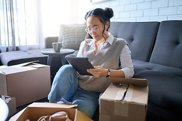 Image showing Real estate, tablet and Asian woman moving into new home while planning or calculating mortgage online. Relocation boxes, technology and female property owner or remote worker in living room of house