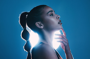 Image showing Woman, beauty and profile of a model thinking in a studio with cosmetics and makeup. Young person, face hand touch and zen female with lighting and blue background isolated feeling relax and calm