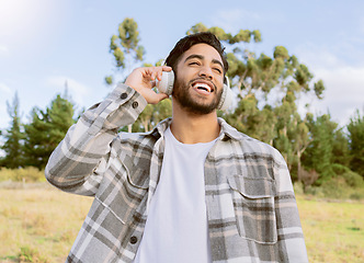 Image showing Music, happy and man relax in a park, smile and laughing at podcast or audio track against nature background. Earphones, laugh and handsome guy listening to online comedy, song or playlist in forest