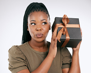 Image showing Box, gift and black woman wonder in studio of package, excited girl and celebration. Curious female, present and surprise for ribbon, background and thinking of birthday giveaway of product promotion