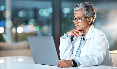 Image showing Laptop, doctor and senior woman in hospital working late or overtime on email, telehealth or research. Bokeh, thinking and female medical physician reading healthcare information at night on computer