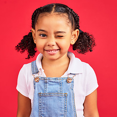 Image showing Portrait, wink and a black child on a red background in studio having fun or feeling carefree. Kids, fashion and smile with a happy female child winking inside on a color wall while looking funny