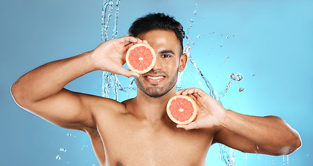 Image showing Man, portrait smile and fruit for skincare, healthy nutrition or vitamin C and hydration against a blue studio background. Happy male holding grapefruit for natural organic diet or body wellness