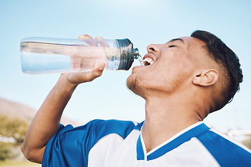 Image showing Water, bottle and football or soccer player on sports field resting after match or competition on a sunny day. Man, athlete and sportsman refreshing during a game happy and smiling for fitness