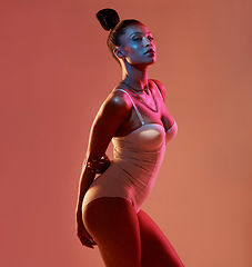 Image showing Portrait, beauty and neon with a model black woman in studio posing in underwear on an orange background. Aesthetic, art and fashion with an attractive young female standing on a kaleidoscope wall