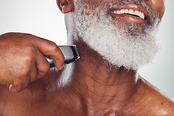 Image showing Hand, beard and shaving with an electric razor with a mature black man in studio on a gray background. Face, grooming and hygiene with a mature male in the bathroom to shave for hair removal