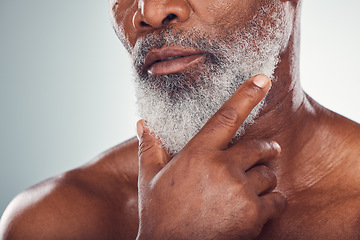 Image showing Hand, beard and skin with a senior black man grooming in studio on a gray background for beauty or skincare. Face, hygiene and cosmetics with a mature male indoor to promote facial hair maintenance