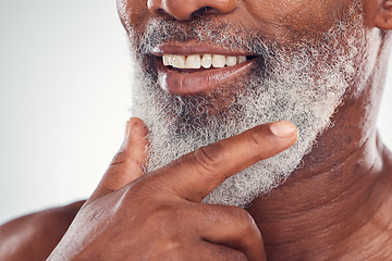 Image showing Hand, beard and smile with a senior black man grooming in studio on a gray background for beauty or skincare. Skin, hygiene and cosmetics with a mature male indoor to promote facial hair maintenance
