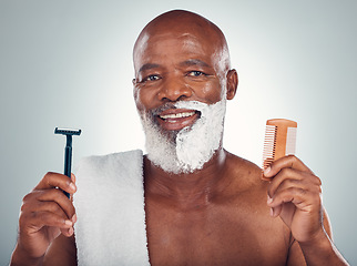 Image showing Black man, portrait smile and beard for shaving with razor, cream and comb for skincare, grooming or self care on a gray studio background. Happy African American male with shave kit for clean facial