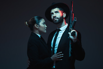 Image showing Couple, fashion or weapon on dark studio background in secret spy, isolated mafia safety or crime lord security. Gangster love, woman or model with gun in stylish, trendy or fashion clothes aesthetic