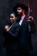 Image showing Gangster couple, fashion or gun on studio background in secret spy, isolated mafia safety or crime lord security. Man, love or model woman with pistol in stylish, trendy or fashion clothes aesthetic