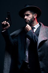 Image showing Gangster, leadership or holding gun on studio background in dark secret spy, isolated mafia or crime lord security. Model, man and hitman suit with weapon in formal style or fashion clothes aesthetic