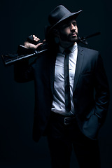 Image showing Hitman, suit or holding gun on studio background in dark secret spy, isolated mafia leadership or crime lord security. Model, man or gangster weapon in formal, fashion clothes or bodyguard aesthetic