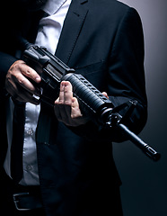 Image showing Gangster, hands or holding gun on studio background in dark secret spy, isolated mafia leadership or crime lord security. Model, man or hitman weapon in suit, fashion clothes or bodyguard aesthetic