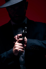 Image showing Gangster, hands or cocking gun on studio background in dark secret spy, isolated mafia leadership or crime safety. Model, assassin or hitman weapon in ready, formal style or fashion clothes aesthetic