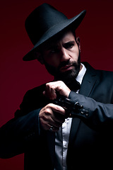 Image showing Gangster, suit or cocking gun on studio background in dark secret spy, isolated mafia leadership or crime safety. Model, assassin or hitman weapon in ready, formal style or fashion clothes aesthetic