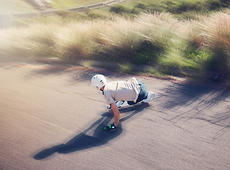 Image showing Skate, blurred motion and fast with a sports man skating on an asphalt road outdoor from the back. Skateboard, soft focus and speed with a male athlete or skater training outside on the street