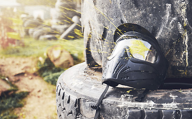 Image showing Field, messy and helmet for a game of paintball, sport and battle in Mexico. Safety, military and protective mask on a tire for physical activity, action and competition in nature, woods or forest