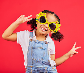 Image showing Funny, sunglasses and girl playful, peace and happiness with young person on red studio background. Portrait, mockup and female child with silly eyewear, fun and creative on break, smile and stylish