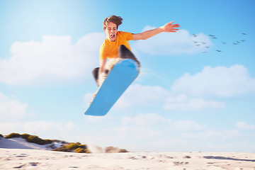 Image showing Sport, sandboard man jumping man in a desert for extreme sports, fitness and training against blue sky background. Sandboarding, jump and guy in dunes with energy, freedom and adrenaline in Dubai